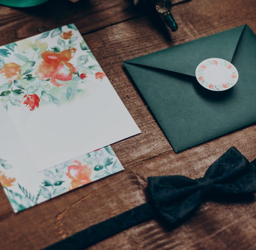 stylish wedding invitation with modern flowers and floral ornaments and bow tie on wooden background top view. rustic wedding morning preparation. space for text