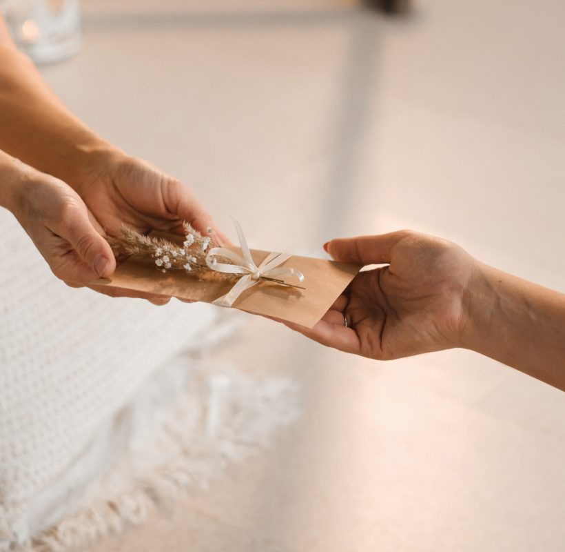 A woman in white clothes passes an envelope with a wish to another woman. The concept of the women's circle.